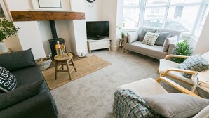 A cozy living room with a fireplace, a television, a sofa, and a window with a city view. - Hyfrydle -  a coastal that sleeps 6 guests  in 3 bedrooms (Beaumaris)