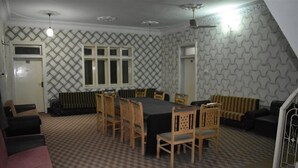 A room with a checkered floor, a dining table with chairs, a radiator, and a patterned wall. - Royal Inn Guest House (Mekhtar)