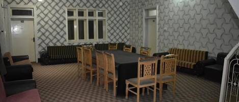 A room with a checkered floor, a dining table with chairs, a radiator, and a patterned wall.
