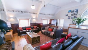 A spacious living room with leather sofas, a wooden coffee table, and a fireplace. - Cwyfan -  a dog that sleeps 8 guests  in 4 bedrooms (Ty Croes)