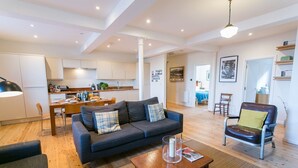 A modern living room with a sofa, a coffee table, and a dining area with a table and chairs. - Coron -  a dog that sleeps 6 guests  in 3 bedrooms (Ty Croes)
