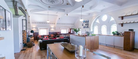 A spacious kitchen with wooden flooring, a central island, and a dining area with a wooden table and chairs.