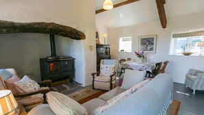 A cozy living room with a stone fireplace, comfortable seating, and a dining area with a table set for two.