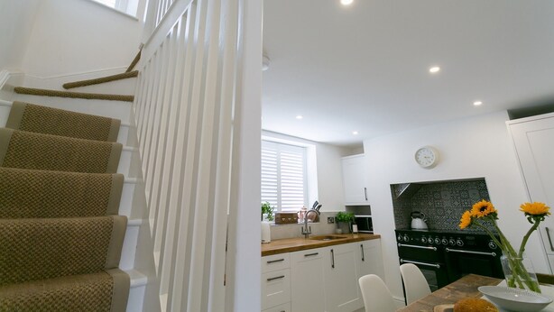 A modern kitchen with white cabinets, a wooden countertop, and a built-in stove. - Shell Cottage -  a dog that sleeps 4 guests  in 2 bedrooms (Menai Bridge)