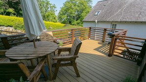 A wooden deck with a table and chairs, a barbecue grill, and a railing. - Shell Cottage -  a dog that sleeps 4 guests  in 2 bedrooms (Menai Bridge)
