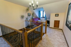 Staircase leads to a spacious interior with a chandelier, potted plant, and artwork.