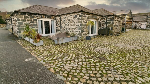 A stone building with a cobblestone driveway and a covered outdoor seating area.