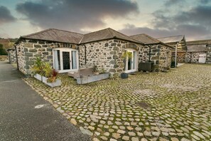 A stone building with a paved driveway and outdoor seating area.