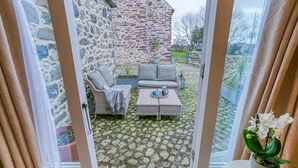 A cozy outdoor seating area with wicker furniture and a stone wall backdrop.