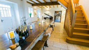 A spacious kitchen with a long wooden counter, a built-in wine rack, and a staircase leading to an upper level. - Tal Y Bont Uchaf Stables -  a hot tub that sleeps 16 guests  in 5 bedrooms (Bangor)