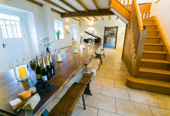 A wooden bar with bottles and candles, a staircase, and a view of the kitchen.