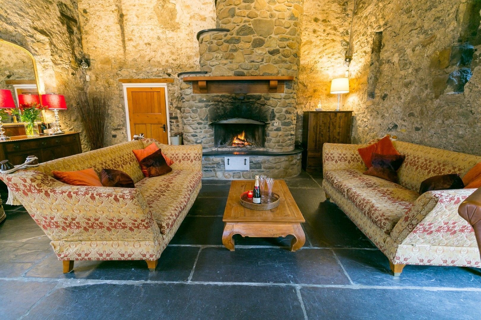 A cozy room with two patterned sofas, a wooden coffee table, and a stone fireplace.