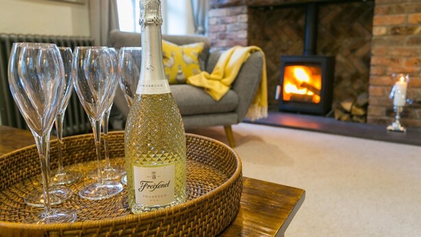Eine Flasche Freixenet Prosecco auf einem gewebten Tablett mit drei leeren Weingläsern.