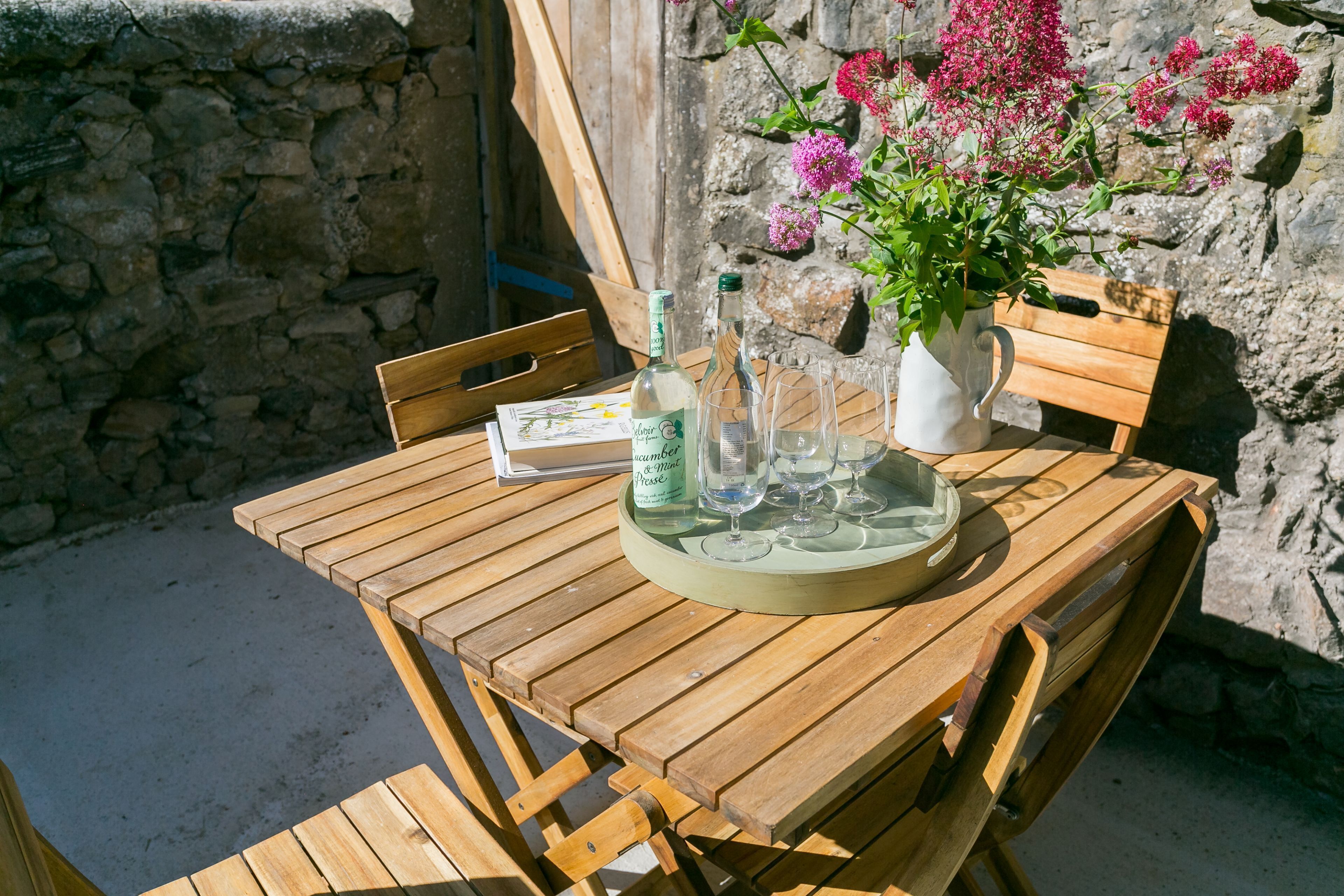 A wooden table with a bottle, glasses, and a pitcher of water.