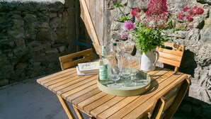Une table en bois avec une bouteille, des verres et une carafe d’eau.
