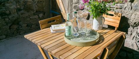 A wooden table with a bottle, glasses, and a pitcher of water.