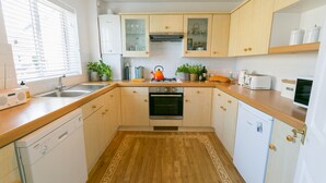 A modern kitchen with wooden cabinets, a built-in oven, a dishwasher, and a toaster. - Sea Bell -  a coastal that sleeps 6 guests  in 3 bedrooms (Holyhead)