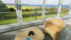 Un balcon avec une chaise en osier et une petite table sur laquelle se trouvent des jumelles et un mot.