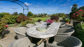 Un espace extérieur aménagé pour les repas, avec des meubles en osier et une table dressée pour un repas.