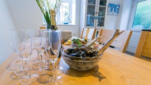 Une table à manger avec des verres à vin, un bol de moules et une bouteille de champagne.