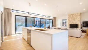 A modern kitchen with a large island, a dining area, and a living room with a fireplace.