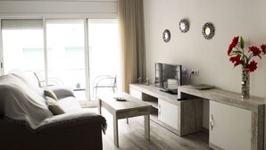 Una sala de estar moderna con sofá, una mesa de centro, televisor y un comedor.