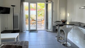Una cocina moderna con comedor, televisor y puerta corredera de vidrio que da a un patio exterior.