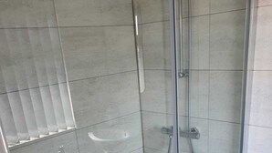 Een moderne badkamer met een douchecabine van glas, een toilet en een wastafel.