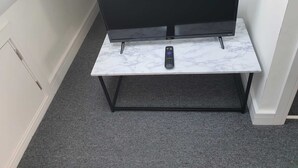 Een flatscreen televisie op een witte marmeren tafel met een afstandsbediening.
