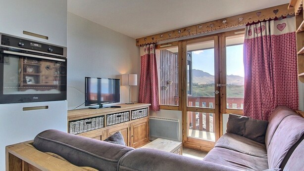 A cozy living room with a sofa, a television, and a wooden cabinet. - Studio cabin for 4 on slopes with balcony (Belle Plagne)