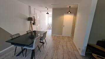 A dining area with a glass table and chairs, a lamp, and a door leading to another room.