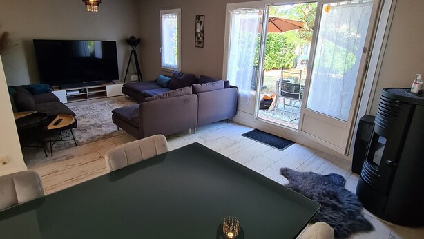 A modern living room with a large flat-screen TV, a sectional sofa, a dining table, and a chandelier. - "Charming 3-Bedroom Cottage with Jacuzzi, Near Loire and Forest, Ouzouer-sur-Loire" (Ouzouer-sur-Loire)
