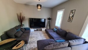 A modern living room with a large flat-screen TV, two sofas, a coffee table, and a decorative plant. - "Charming 3-Bedroom Cottage with Jacuzzi, Near Loire and Forest, Ouzouer-sur-Loire" (Ouzouer-sur-Loire)