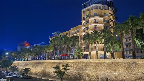 A multi-story hotel with balconies, palm trees, and a stone retaining wall. - Gate Twenty Two Boutique Hotel (Nicosia)