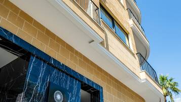 Un hotel de varios pisos con diseño moderno, que cuenta con balcones y una entrada destacada con fachada de mármol.