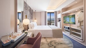 A modern hotel room with a large bed, a TV, a vanity with a mirror, and a view of the city. - Gate Twenty Two Boutique Hotel (Nicosia)