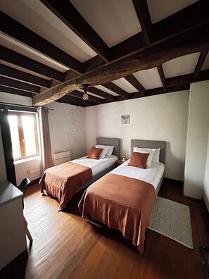 Ein Zimmer mit zwei Betten, einem Schreibtisch und einem Fenster.