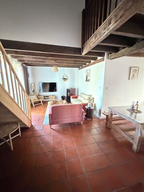 A living room with a sofa, a coffee table, and a TV. There is a staircase leading to an upper level.
