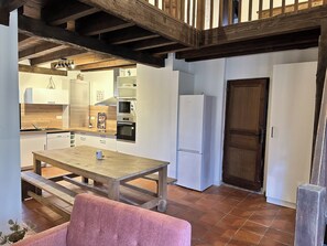 Een moderne keuken met een houten tafel, witte kastjes en een grote oven.
