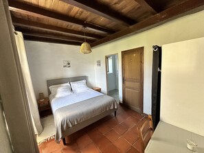 Une chambre à coucher avec un lit, une porte en bois, une douche et un luminaire suspendu.