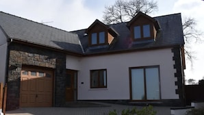 Ein modernes, zweistöckiges Haus mit einer Fassade aus Naturstein, einer Garage und einer großen Schiebeglastür.