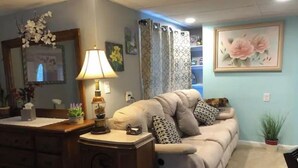 Ein Wohnzimmer mit einer Couch, einer Lampe, einem Spiegel und einem Gemälde an der Wand.