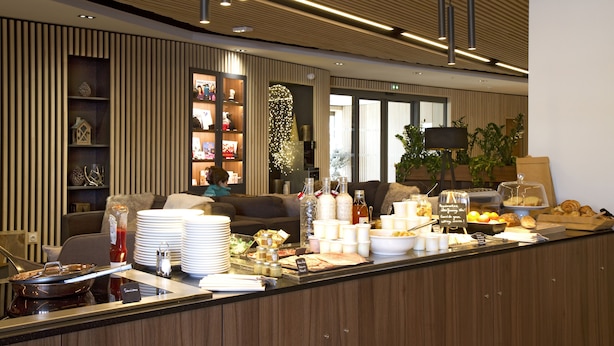Un hall d’hôtel moderne avec un comptoir d’accueil, un espace salon et une grande fenêtre.