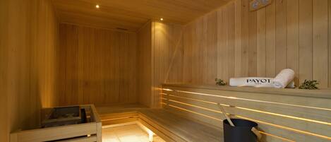 A wooden sauna with benches, a towel, and a bucket.