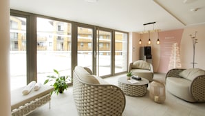 Un hall d’hôtel moderne, doté de grandes fenêtres, de meubles en osier et d’un design minimaliste.