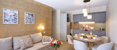 Una sala moderna con sofá, mesa de centro y comedor con sillas y una mesa dispuesta para el desayuno.