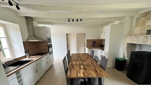 A modern kitchen with a wooden dining table, white cabinets, and a black range hood. - Charming gîte "chez Lisa" 91m2 (Saint-Just)