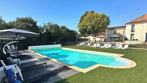 A backyard with a swimming pool, surrounded by artificial grass, lounge chairs, and umbrellas. - Charming gîte "chez Lisa" 91m2 (Saint-Just)