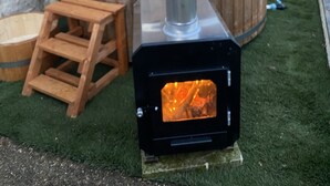 A wood-burning stove with a chimney, a wooden hot tub, and a wooden bench in a backyard. - Charming gîte "chez Lisa" 91m2 (Saint-Just)