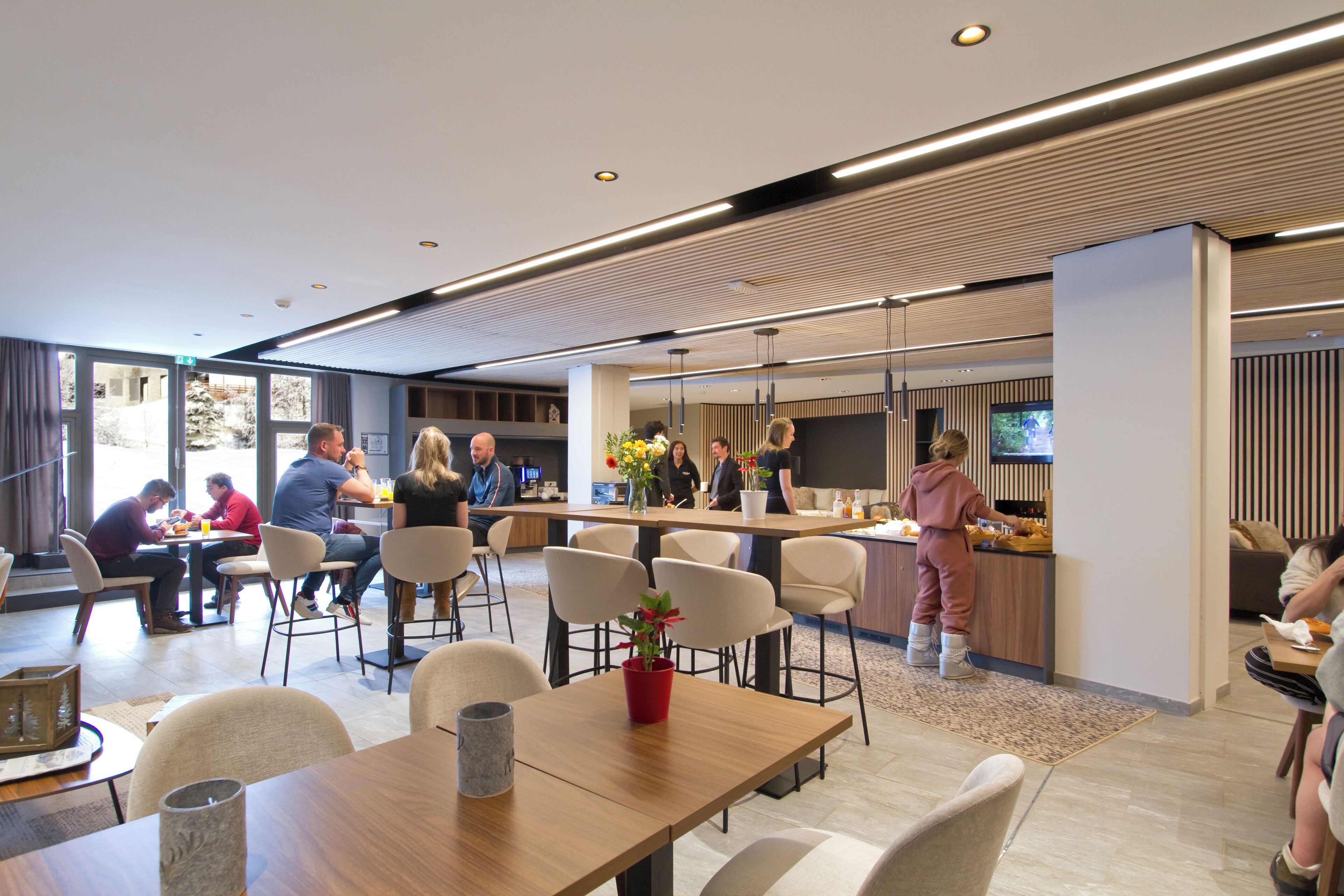 A modern dining area with tables, chairs, and a bar area with a person preparing food.